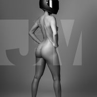 Black and white photo of confident nude woman wearing a black motorcyle helmet and black high heels standing with back to camera looking over shoulder.