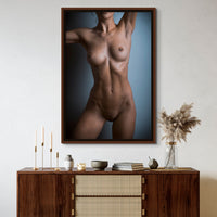 Framed canvas artwork hanging above a brown walnut credenza, the art is a fine art photo of a nude woman standing facing the camera. The photo is cropped to show the model from her chin to her mid thigh.