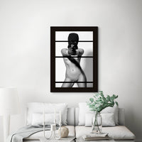 Framed fine art photo hanging above a sofa in a stylish livingroom of a nude woman wearing a black balaclava and black gloves holding a handgun, looking and pointing the gun directly at the camera.