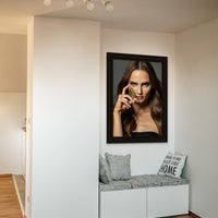 A reading nook in a modern minimalist home, with a large canvas art piece hanging above the built in seating. The artwork is a close up portrait of a beautiful woman holding a bullet between her thumb and forefinger, in front of her face and looking directly at the camera.