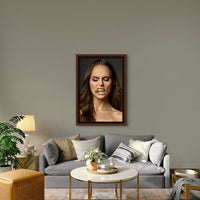 Framed photography artwork hanging above the sofa in a boho-glam style livingroom, the art is a portrait of a beautiful woman holding a bullet between her teeth with her brow furrowed.