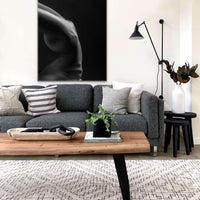 Large canvas artwork hanging above a sofa in a modern livingroom, the artwork is a black and white photo showing a sideview of a naked woman in a handstand pose with back arched, the photo is cropped to show only her torso.