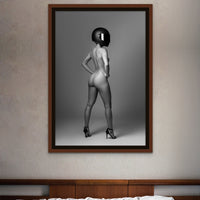 Framed black and white photo of confident nude woman wearing a black motorcyle helmet and black high heels standing with back to camera looking over shoulder.