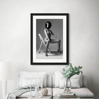 Black and white framed photo of nude woman hanging above white sofa