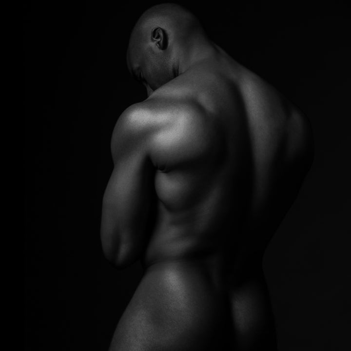 Black and white fine art photo of fine nude black man posterior view from head to mid thigh.