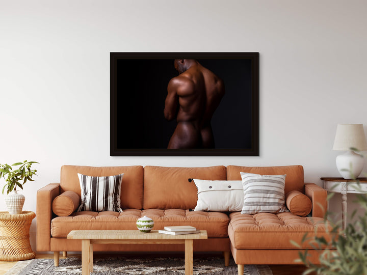 Neutral living room with framed portrait of a nude black man with back turned to camera.