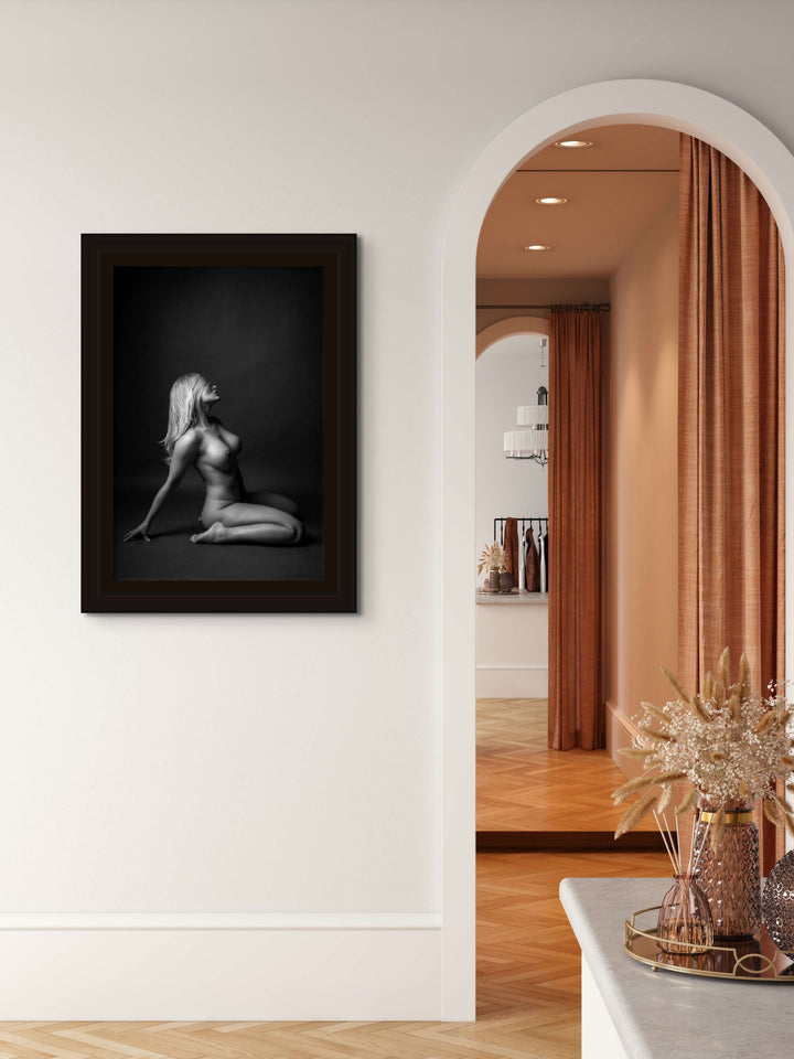 Artwork hanging on a bedroom wall beside an arched entry into the ensuite displaying a beautiful simple photo showing a sideview of a nude woman sitting on her knees, leaning back with her hair swept across her face.