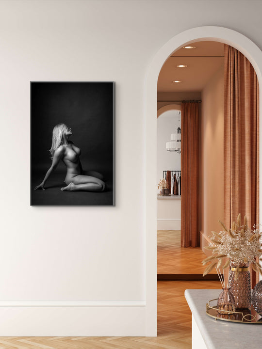 Artwork hanging on a bedroom wall beside an arched entry into the ensuite displaying a beautiful simple photo showing a sideview of a nude woman sitting on her knees, leaning back with her hair swept across her face.