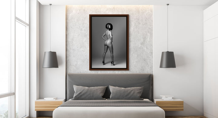 Modern bedroom with artwork hanging above headboard. The artwork is a black and white photo of confident nude woman wearing a black motorcyle helmet and black high heels standing with back to camera looking over shoulder.