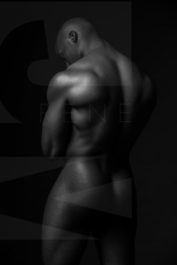  Black and white fine art photo of a nude black man posterior view from head to mid thigh with arms crossed, looking downwards.