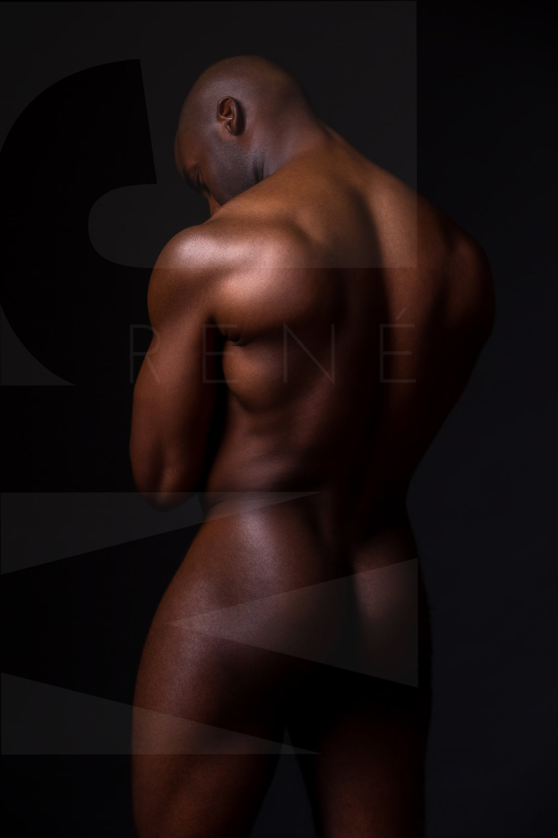 Fine art photo of nude black man posterior view from head to mid thigh with arms crossed, looking downwards.