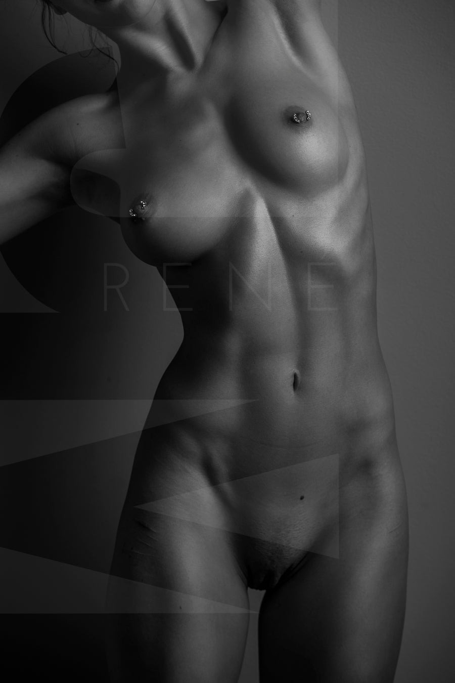 Black and white fine art photo of a nude woman standing facing the camera. The photo is cropped to show the model from her chin to her mid thigh. 