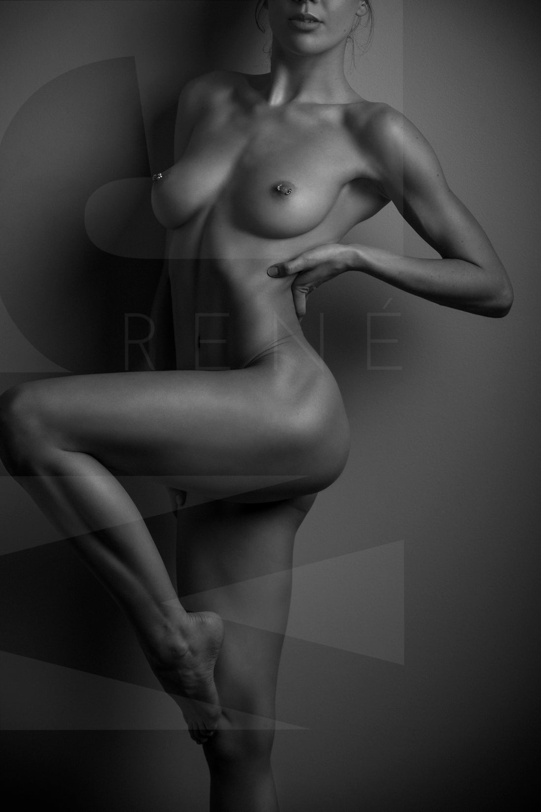 Black and white fine art photo of nude woman from her chin to her knee, showcasing her lines and curves by standing one one leg with the other knee bent so we can see the full length of her leg.