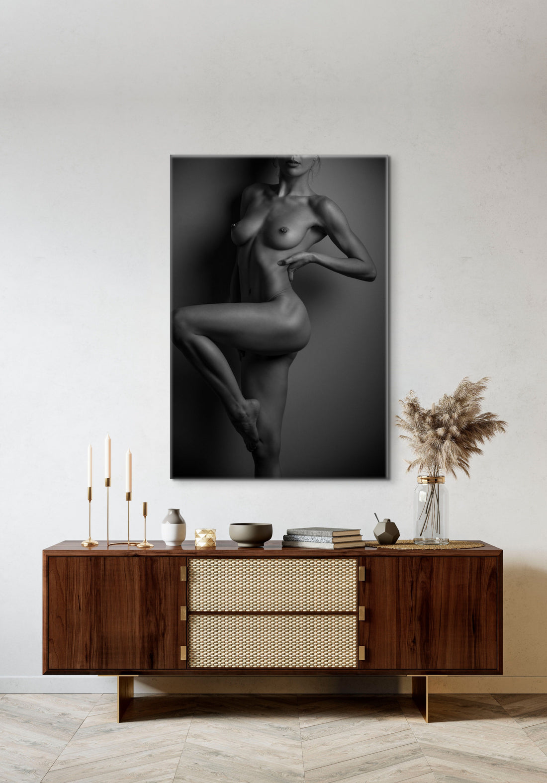 Canvas wall art hanging above a brown walnut credenza, the art is a black and white fine art photo of nude woman from her chin to her knee, showcasing her lines and curves by standing one one leg with the other knee bent so we can see the full length of her leg.