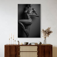 Canvas wall art hanging above a brown walnut credenza, the art is a black and white fine art photo of nude woman from her chin to her knee, showcasing her lines and curves by standing one one leg with the other knee bent so we can see the full length of her leg.