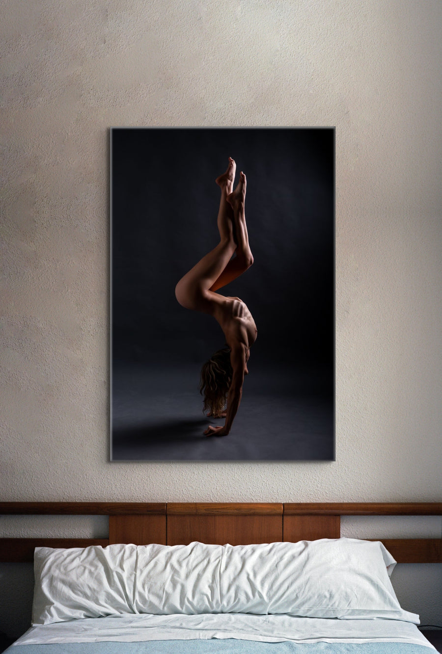 Bedroom wall with picture of nude woman in acrobatic pose hanging above headboard