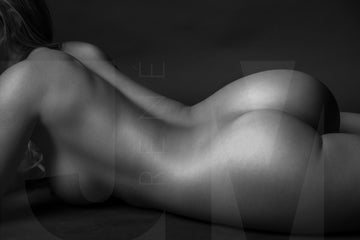 Close up of a black and white nude woman portrait. The woman is lying on her side, the image is cropped to show from her shoulders to the top of her thighs.