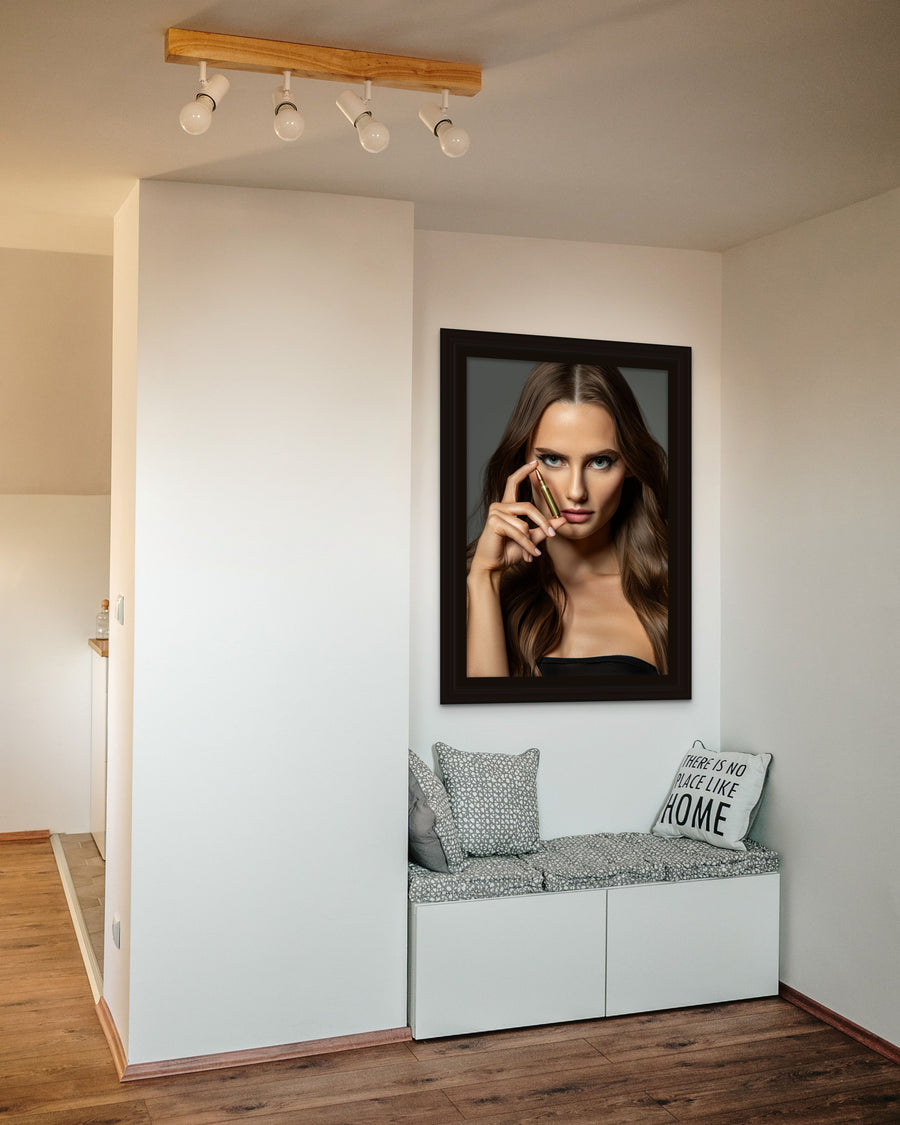A reading nook in a modern minimalist home, with a large canvas art piece hanging above the built in seating. The artwork is a close up portrait of a beautiful woman holding a bullet between her thumb and forefinger, in front of her face and looking directly at the camera.