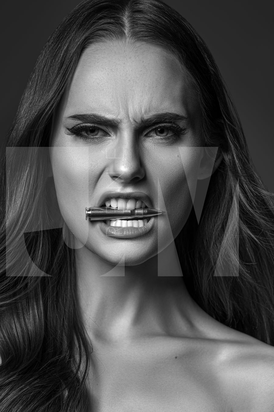 Close up black and white portrait of a beautiful woman holding a bullet between her teeth with her brow furrowed.