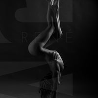 A black and white image showing a side body view of a nude woman in a handstand pose with arched back and crossed bent legs.