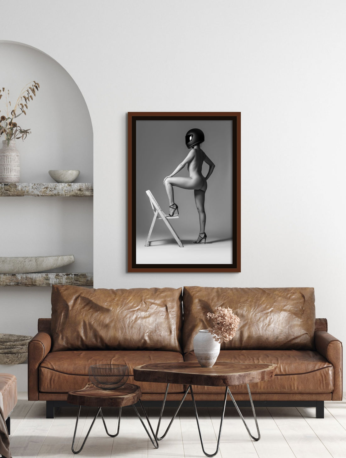 Framed fine art photography of nude woman hanging above brown leather sofa